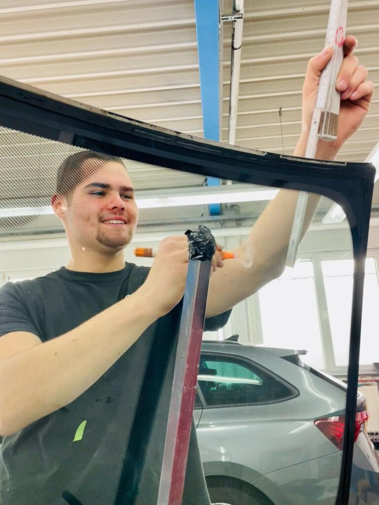 Mitarbeiter setzt eine neue Windschutzscheibe ein – Autoglas-Service Fix Auto Cottbus